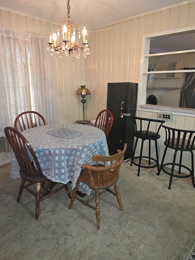 dining area with wood walls, carpet floors, a chandelier, and ornamental molding