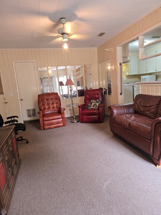 carpeted living room featuring ceiling fan and wooden walls