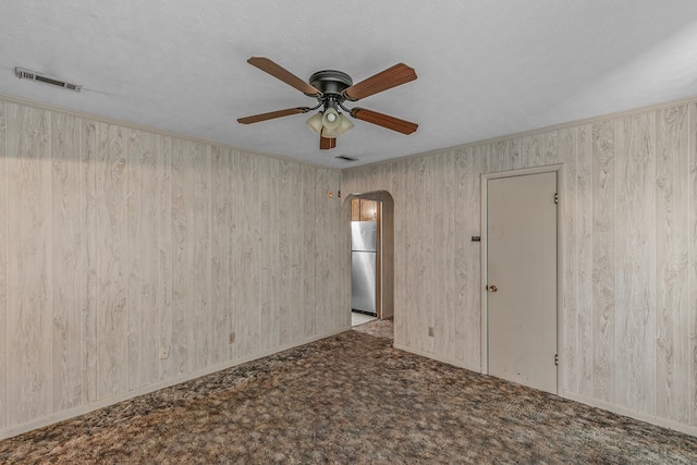 155 Sharon Ln, Ozark, AL 36360 - spare room featuring arched walkways, ceiling fan, carpet floors, and wooden walls