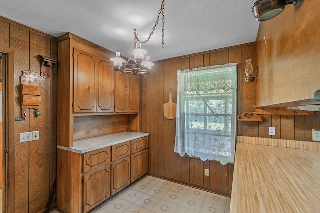 155 Sharon Ln, Ozark, AL 36360 - kitchen featuring wooden walls, brown cabinetry, light countertops, a chandelier, and pendant lighting