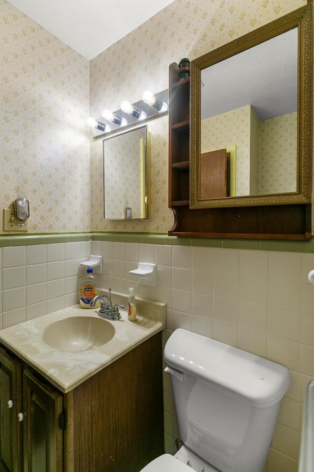155 Sharon Ln, Ozark, AL 36360 - bathroom with wallpapered walls, wainscoting, tile walls, toilet, and vanity