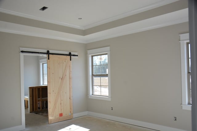 unfurnished bedroom featuring a tray ceiling, a barn door, and crown molding