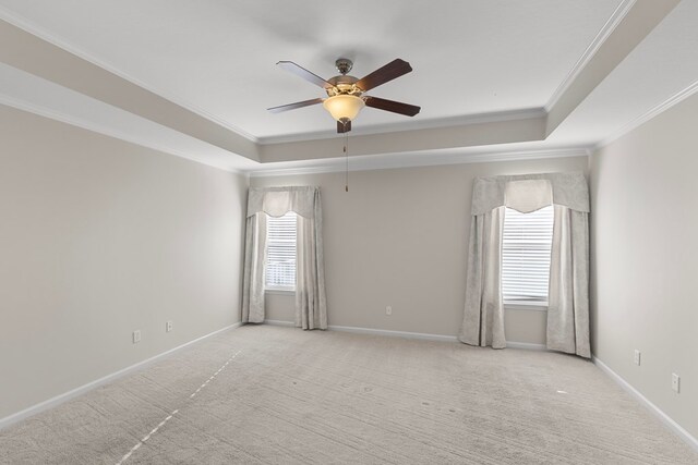 unfurnished room with a raised ceiling, crown molding, ceiling fan, and light colored carpet