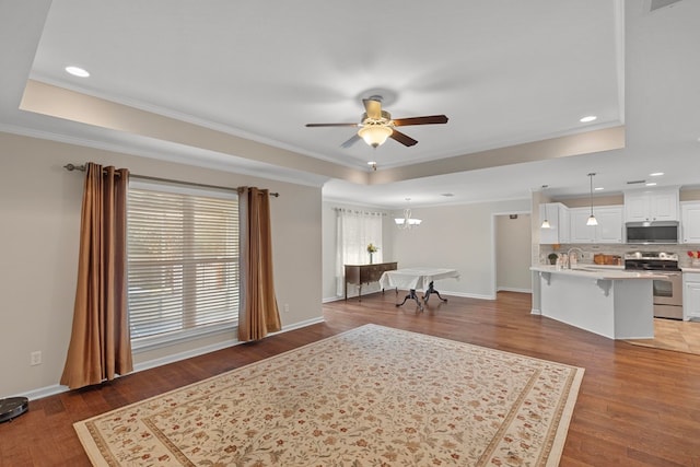 living room with dark hardwood / wood-style flooring, ceiling fan with notable chandelier, and ornamental molding