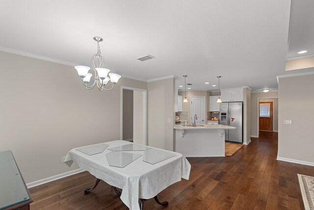 dining room featuring sink, an inviting chandelier, dark hardwood / wood-style floors, and ornamental molding