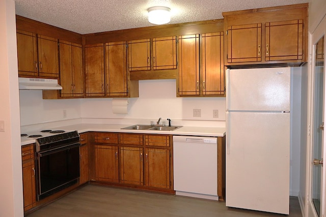 kitchen featuring sink, a textured ceiling, white appliances, and light wood-type flooring