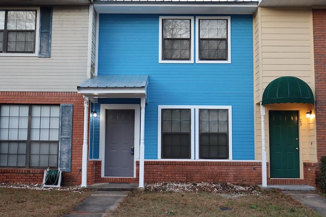 doorway to property with metal roof and brick siding