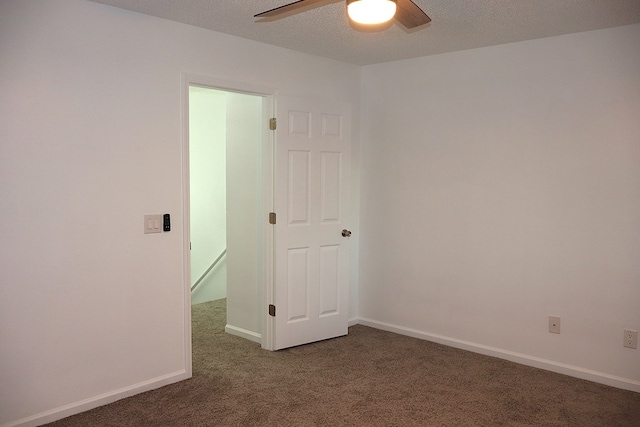 spare room with ceiling fan and dark colored carpet