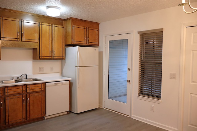 kitchen with sink, a textured ceiling, white appliances, and light hardwood / wood-style flooring