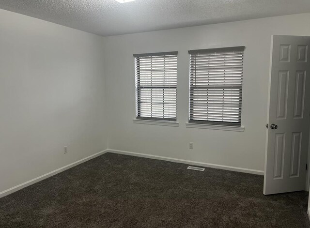 unfurnished room with baseboards, dark colored carpet, and a textured ceiling