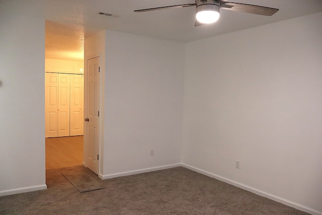 carpeted empty room with baseboards, visible vents, and a ceiling fan