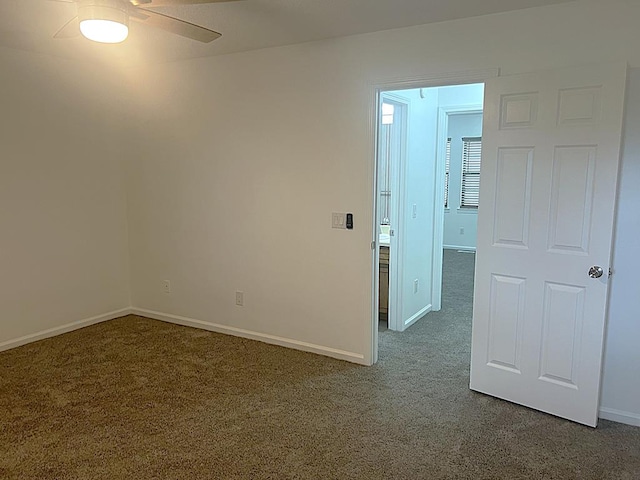 unfurnished room with ceiling fan, dark carpet, and baseboards