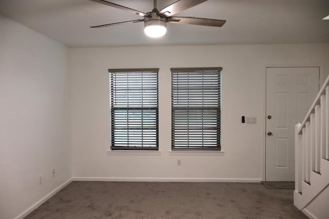 unfurnished room featuring baseboards, dark colored carpet, and a ceiling fan