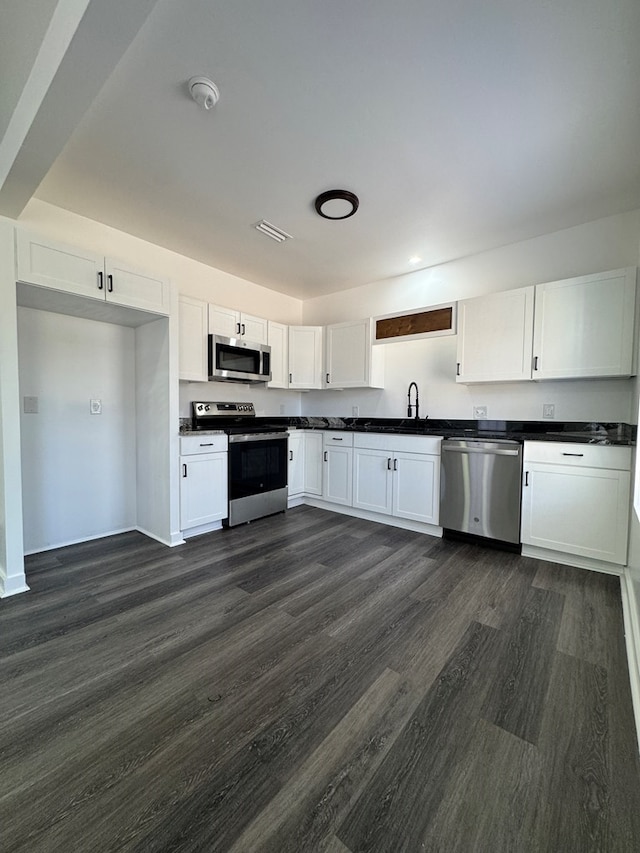 kitchen with white cabinetry, appliances with stainless steel finishes, dark hardwood / wood-style floors, and sink