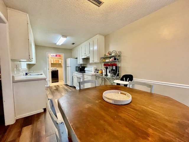 dining area with washer / clothes dryer, sink, light hardwood / wood-style floors, and a textured ceiling