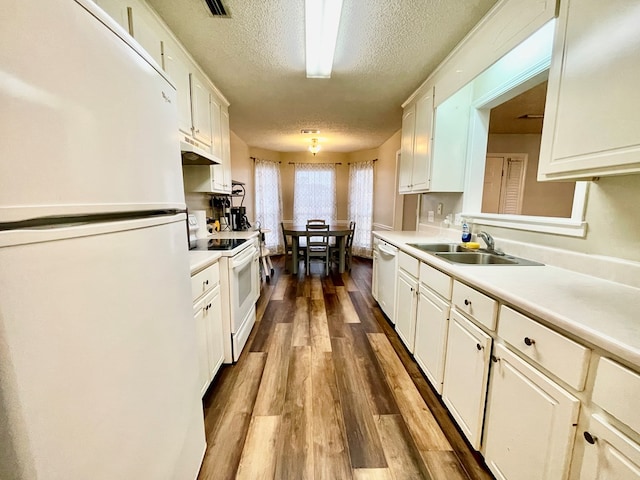 kitchen with white appliances, sink, hardwood / wood-style flooring, a textured ceiling, and white cabinetry