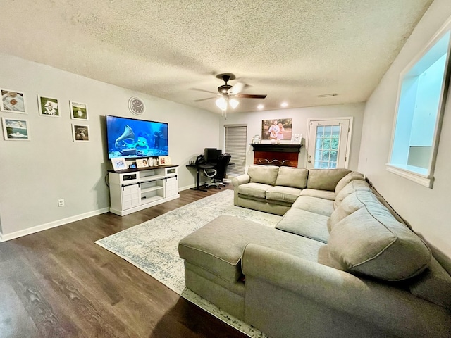 living room with ceiling fan, dark wood-type flooring, and a textured ceiling