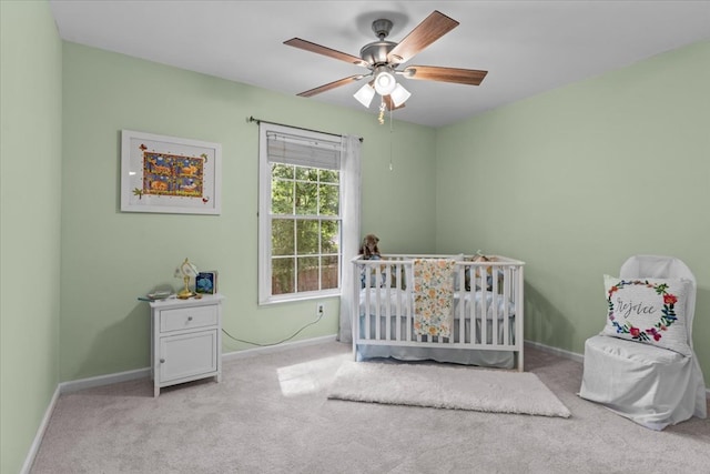 carpeted bedroom with ceiling fan and a crib