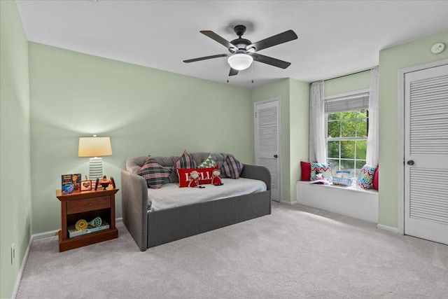 carpeted bedroom featuring ceiling fan and two closets