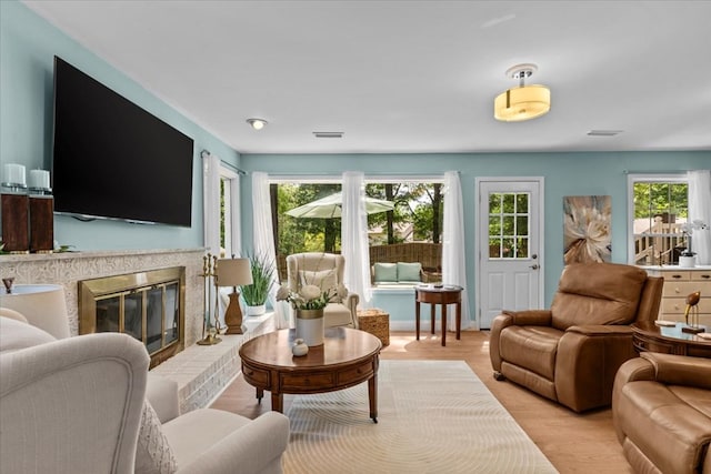 living room featuring light wood-type flooring, a wealth of natural light, and a fireplace