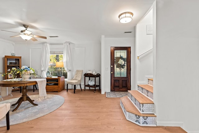 entrance foyer with ceiling fan, ornamental molding, and light hardwood / wood-style floors