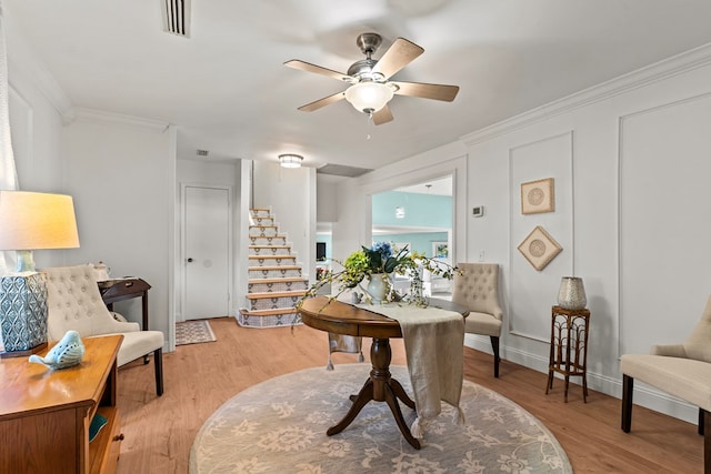 living area featuring light wood-type flooring, ceiling fan, and crown molding