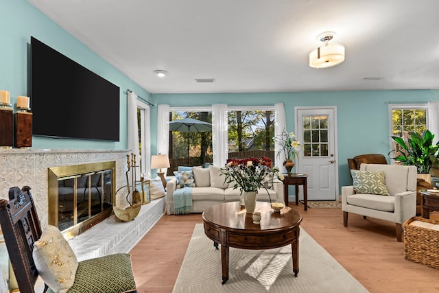 living room featuring a brick fireplace, a wealth of natural light, and light wood-type flooring