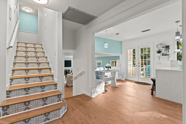 staircase with hardwood / wood-style floors and french doors