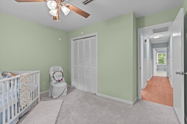 bedroom featuring light carpet, a closet, a nursery area, and ceiling fan