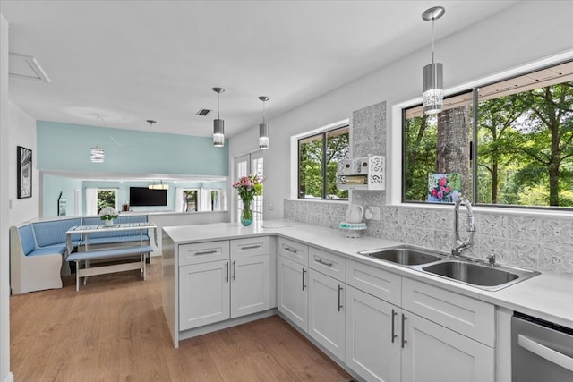 kitchen with pendant lighting, white cabinets, tasteful backsplash, sink, and stainless steel dishwasher