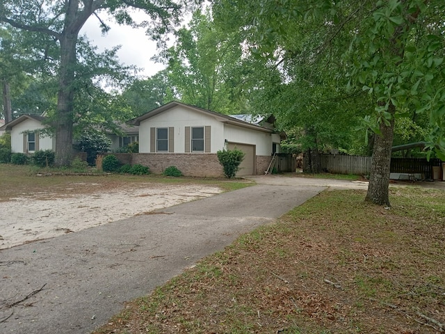 single story home with a garage, brick siding, fence, and concrete driveway