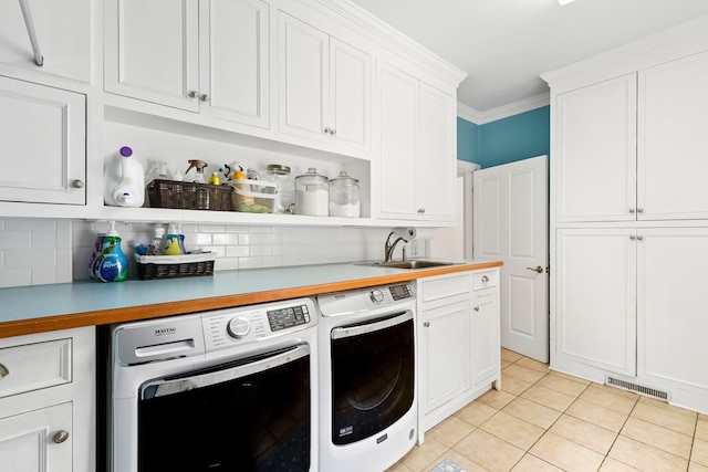 4 Woodmere Dr, Dothan, AL 36305 - laundry room featuring washing machine and clothes dryer, light tile patterned flooring, cabinet space, and ornamental molding