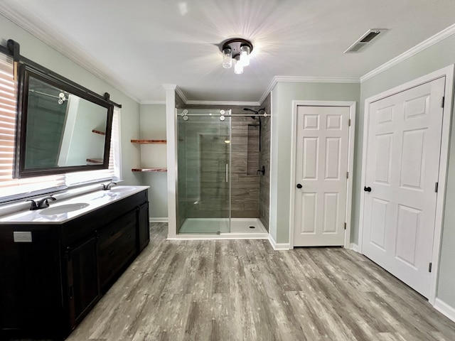 bathroom with wood finished floors, a sink, visible vents, a shower stall, and crown molding