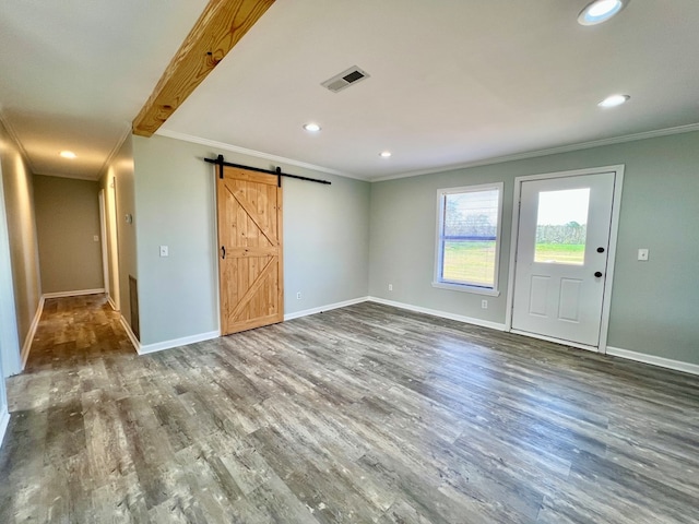 interior space featuring baseboards, a barn door, visible vents, and wood finished floors
