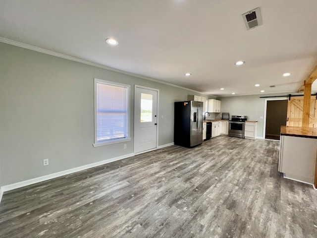 kitchen with a barn door, visible vents, appliances with stainless steel finishes, dark wood-style flooring, and white cabinetry