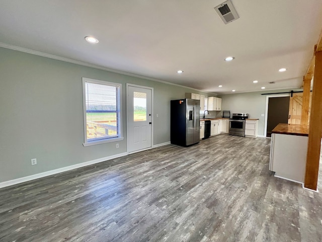 kitchen featuring dark wood finished floors, visible vents, a barn door, appliances with stainless steel finishes, and white cabinets
