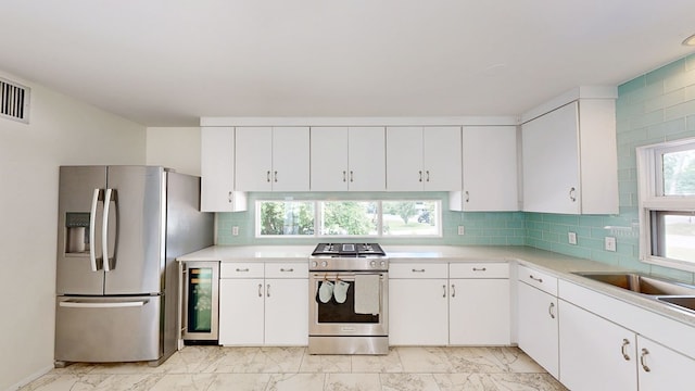 kitchen with stainless steel appliances, white cabinets, light countertops, marble finish floor, and wine cooler