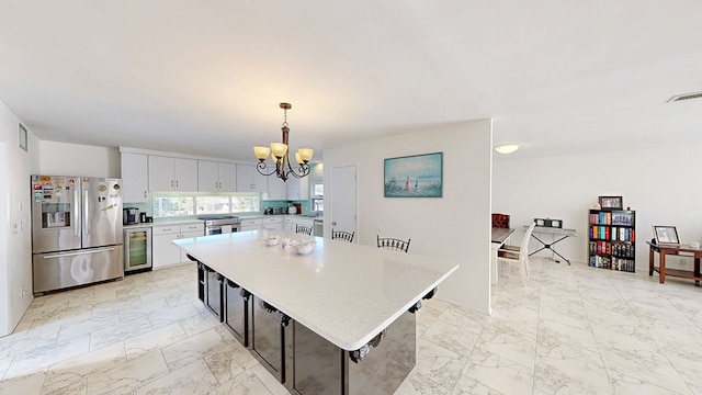 kitchen with a chandelier, wine cooler, marble finish floor, appliances with stainless steel finishes, and light countertops