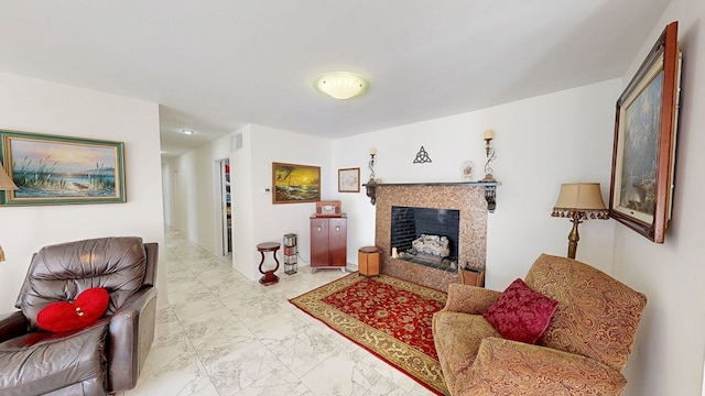 living area with a tile fireplace, marble finish floor, and visible vents