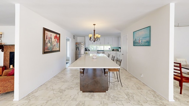 dining area with marble finish floor, a fireplace, and an inviting chandelier