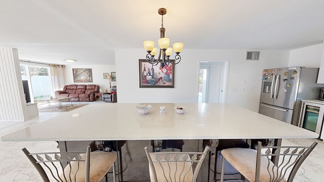 kitchen with beverage cooler, visible vents, a breakfast bar, marble finish floor, and a notable chandelier