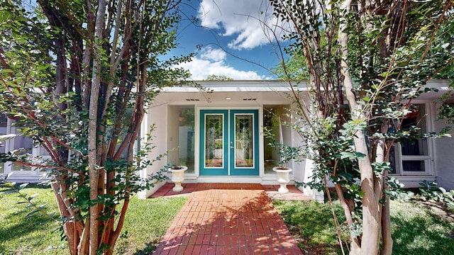 view of exterior entry featuring french doors and stucco siding