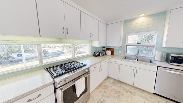 kitchen featuring stainless steel appliances, marble finish floor, light countertops, and a sink