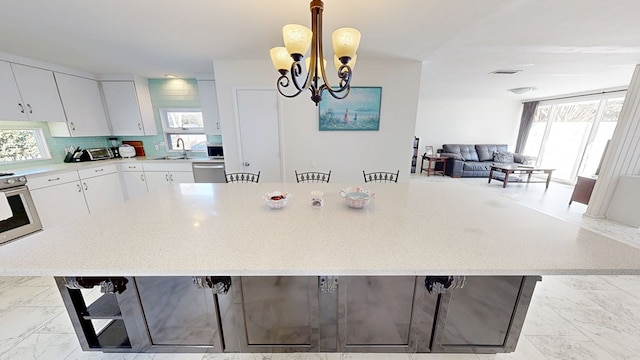 kitchen featuring a sink, white cabinets, marble finish floor, light countertops, and appliances with stainless steel finishes