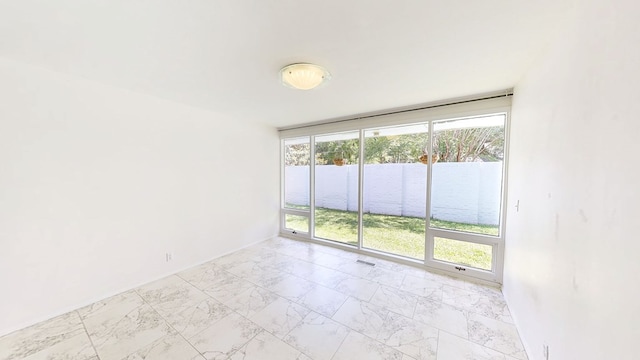 unfurnished room featuring marble finish floor, a healthy amount of sunlight, and visible vents