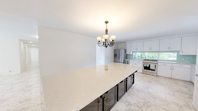 kitchen featuring an inviting chandelier, backsplash, appliances with stainless steel finishes, a kitchen island, and marble finish floor
