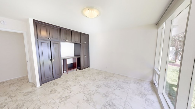 unfurnished bedroom with light marble finish flooring and baseboards