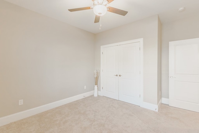 unfurnished bedroom with ceiling fan, light colored carpet, and a closet