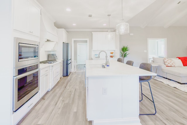 kitchen featuring a kitchen breakfast bar, stainless steel appliances, pendant lighting, beamed ceiling, and white cabinets