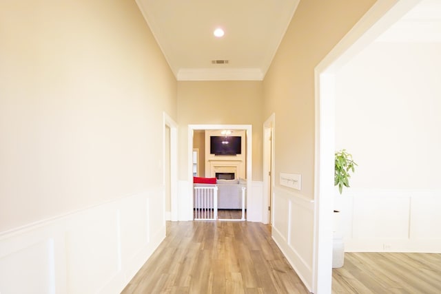 corridor with light hardwood / wood-style floors and ornamental molding